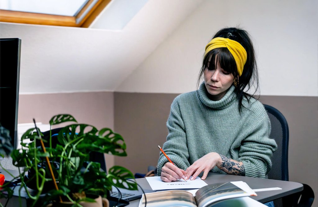 Kreative Arbeit am Schreibtisch mit Notizbuch und Pflanzen – Entwicklung visueller Kommunikation