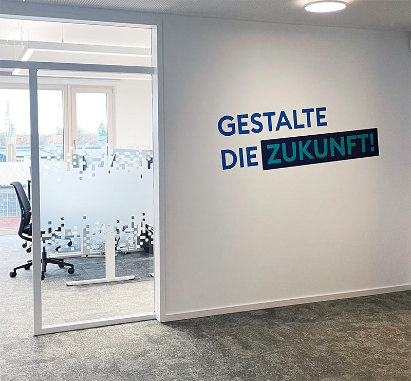 Wandgestaltung mit Schriftzug 'Gestalte die Zukunft' – visuelle Kommunikation im Büro